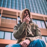 Capo Beatz posing in front of an urban office tower during a captivating photoshoot.