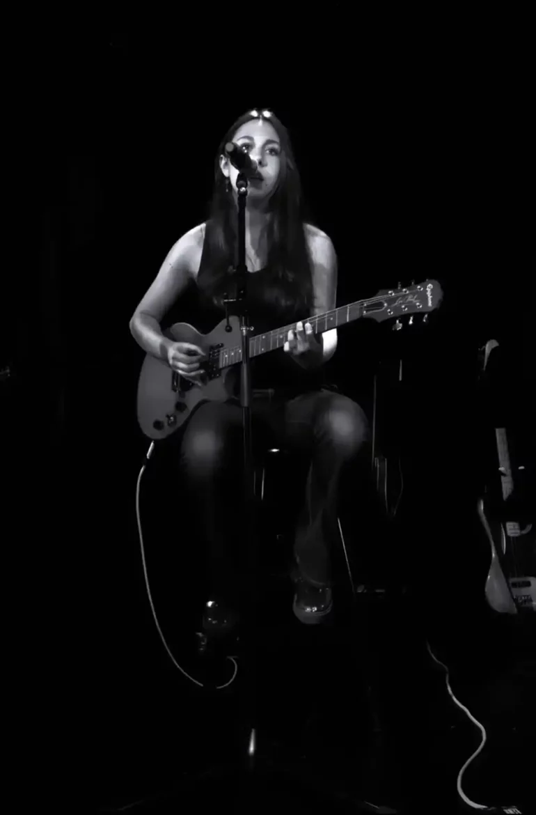  Amelie Lucille performing on stage, sitting with her guitar