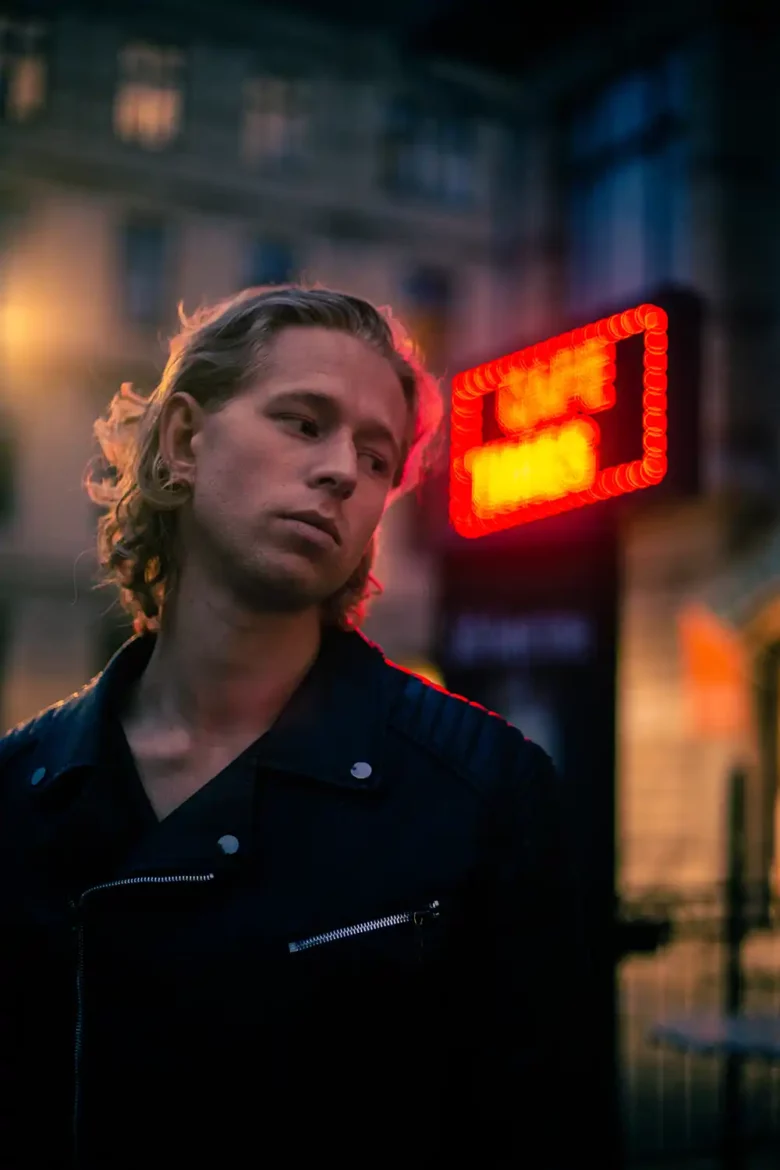 Tom Hamstrom posing in front of a neon sign, exuding retro vibes.