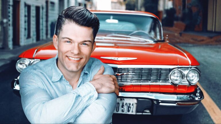 Nick Pritchard leaning on a classic red car, representing his single "1961"