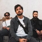 Mont Rouge band members sitting casually in a rustic room with peeling walls.