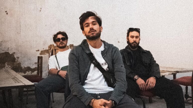 Mont Rouge band members sitting casually in a rustic room with peeling walls.