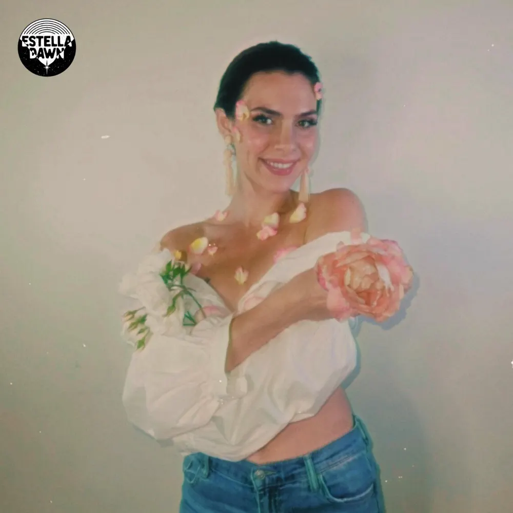 Estella Dawn posing with flowers in a soft focus, promoting her new song "514 Denim."