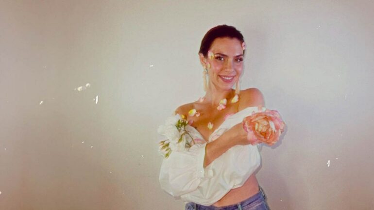 Estella Dawn posing with flowers in a soft focus, promoting her new song "514 Denim."