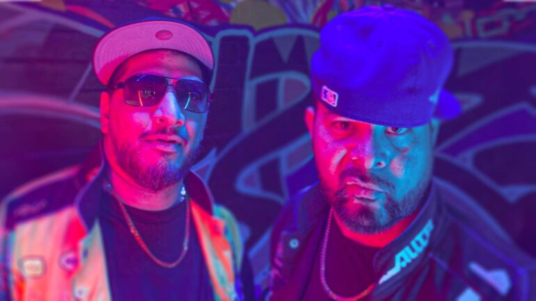 Fuzzy Bear duo Riaz and Kobie pose in colorful lighting, promoting their new single "Tokyo Express."