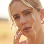 Close-up of Lena Grand with a serene expression, wearing gold hoop earrings and a soft, thoughtful gaze.