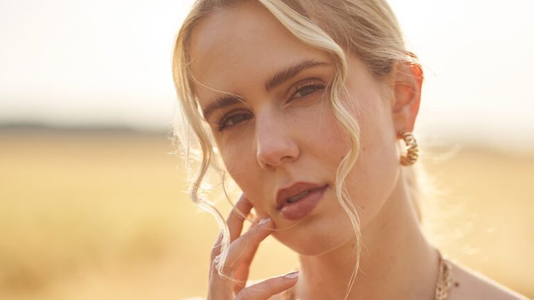 Close-up of Lena Grand with a serene expression, wearing gold hoop earrings and a soft, thoughtful gaze.