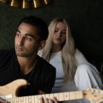 AJ Chaney playing guitar with a woman sitting behind him, reflecting the emotional tone of his debut single "Fading."