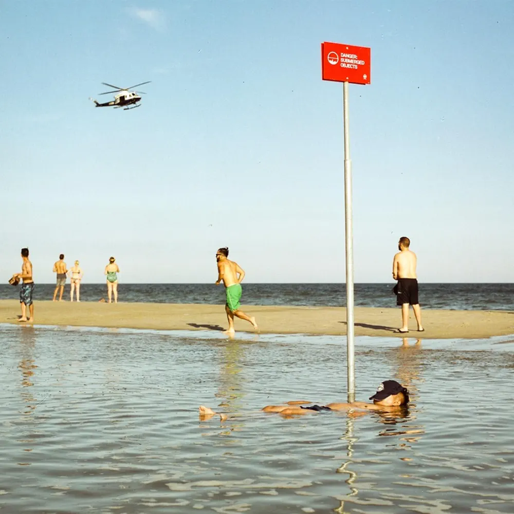 Beach scene with people and a warning sign, MORENAUX's "Cruel" cover