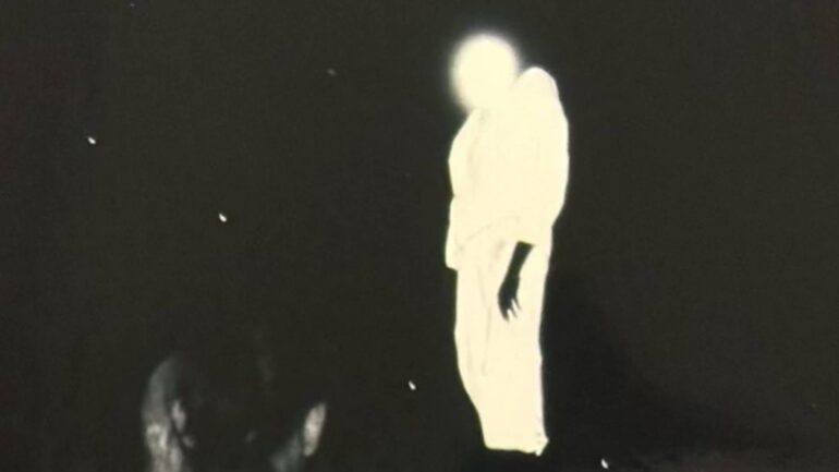 Distorted image of Kanye West glowing among a crowd dressed in white during his South Korea concert.