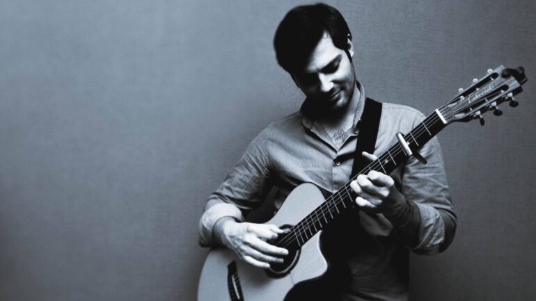 Emilio Lanza playing acoustic guitar in a black and white image, highlighting his emotional connection to music.