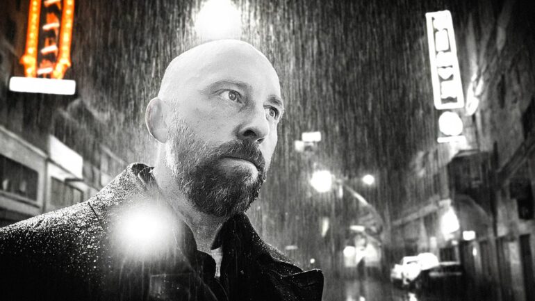 Kelly Murphy in a rain-soaked urban street, reflecting the mood of his new single 'Pressure'.