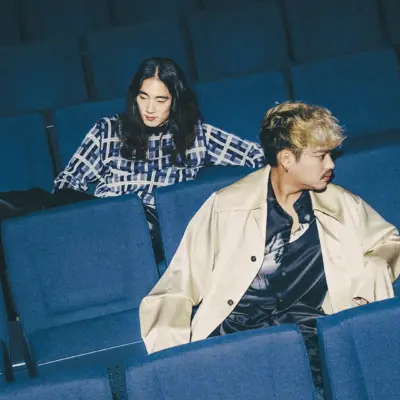 Photo of The fin., a Japanese indie band, seated in a theater with blue chairs, showcasing their relaxed and stylish aesthetic.