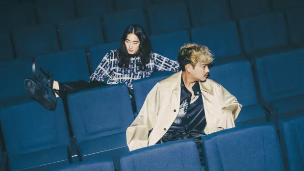 Photo of The fin., a Japanese indie band, seated in a theater with blue chairs, showcasing their relaxed and stylish aesthetic.