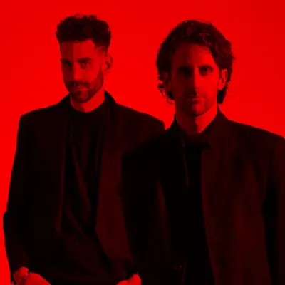 The Listros band members standing against a bold red background, wearing dark outfits, highlighting their intense and edgy aesthetic.